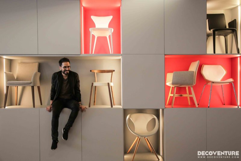 Georges Abou Chabke sitting next to designers chairs.